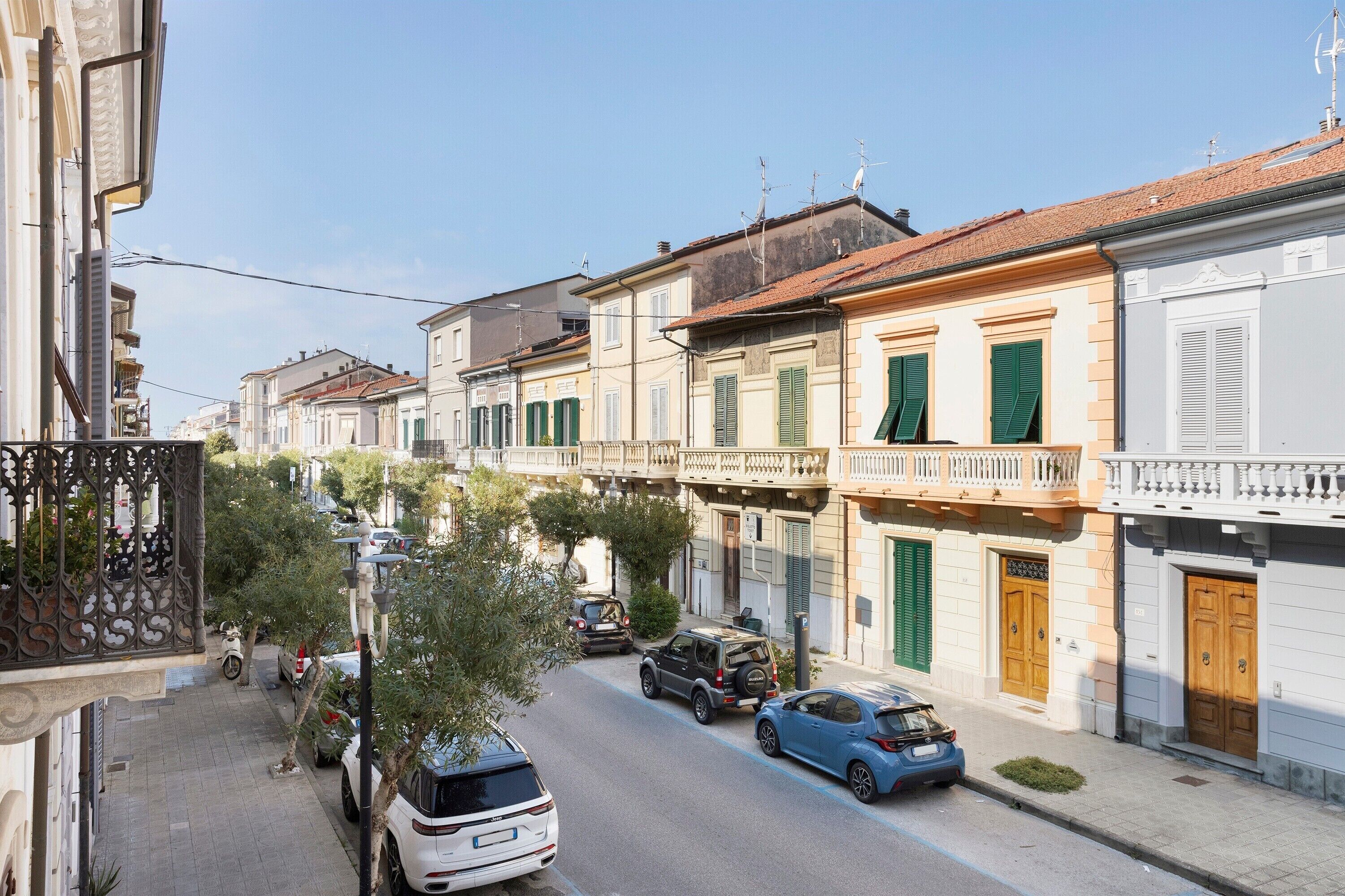 A street view with buildings, parked cars, and a scooter.