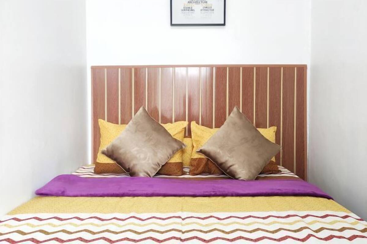 A bed with a wooden headboard, two pillows, and a patterned bedspread.