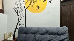 A room with a bed, a wall with a tree and birds illustration, and a door. - Semarang Inn Syariah (Gayamsari)