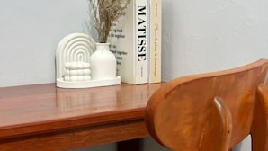 A wooden desk with a white vase and books. - Semarang Inn Syariah (Gayamsari)