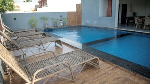 Une piscine avec des chaises longues et des plantes en pot.