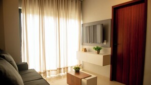 Un salon moderne avec un canapé, une table basse, un téléviseur fixé au mur et une porte en bois.