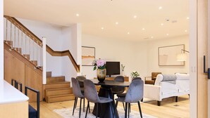 Een moderne woonkamer met een eethoek, een trap en een flatscreen televisie.