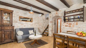 Um quarto rústico com paredes de pedra, uma mesa de jantar de madeira, um sofá e um armário.