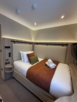 Una habitación de hotel moderna con una cama grande, una mesita de noche y un estante empotrado.