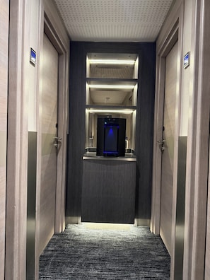 A hotel hallway with a central elevator, wooden doors, and a carpeted floor. - Mabledon Court Hotel (London)