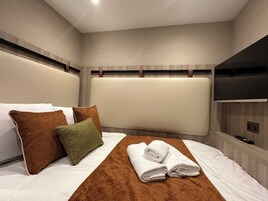 Ein Hotelzimmer mit einem großen Bett, einem flachbildfernseher an der Wand und einem Holzkopfende.
