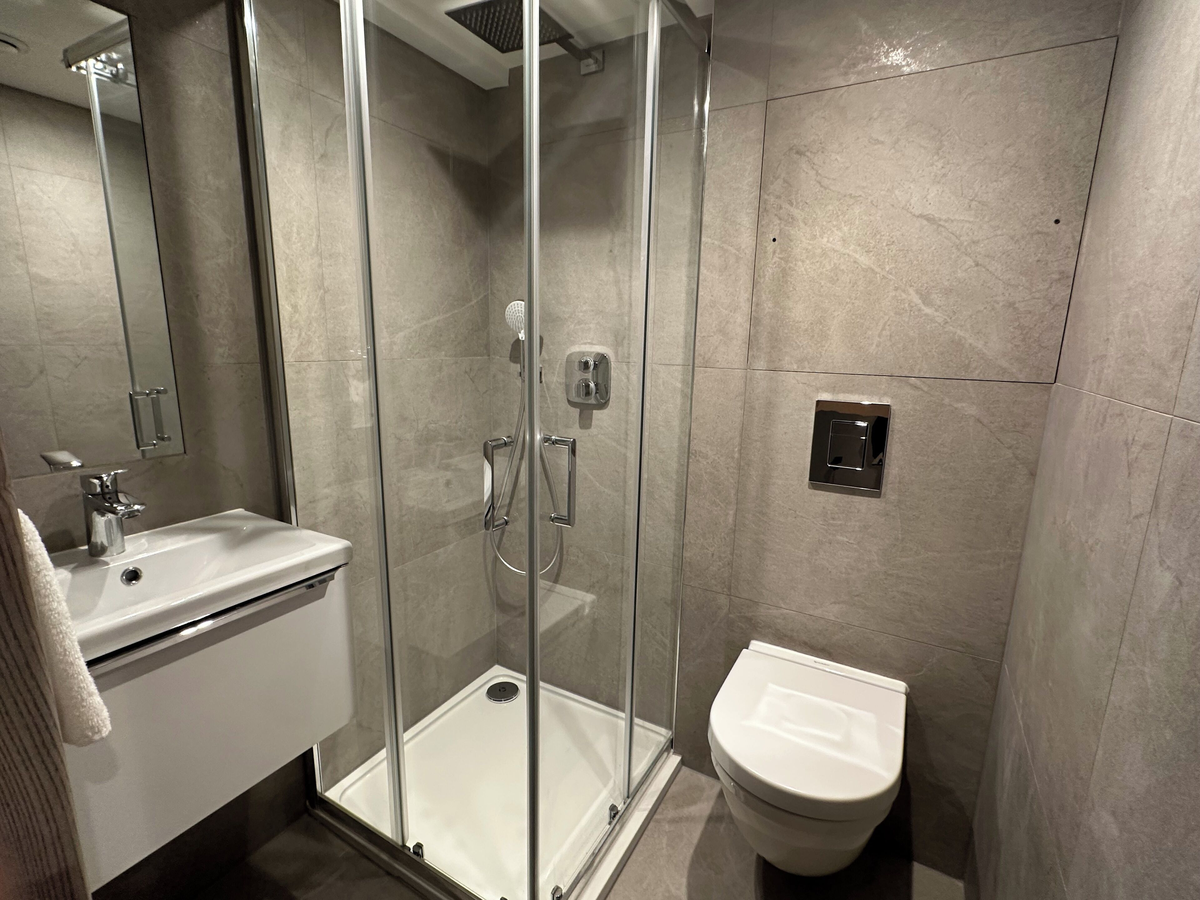 Une salle de bain moderne avec une douche à parois de verre, un lavabo blanc et des toilettes.