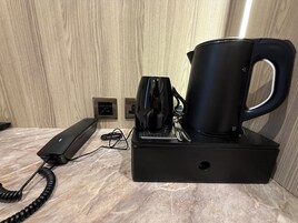 Una cafetera sobre un pedestal negro, con el cable de alimentación conectado a un enchufe de pared.