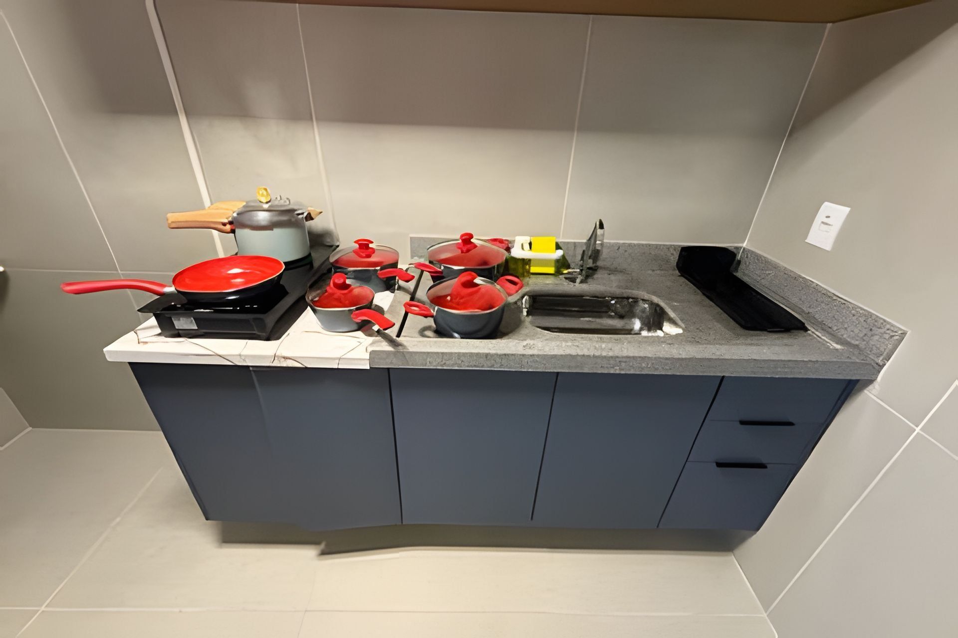 Una cocina compacta con gabinetes grises, un lavamanos y diversos utensilios y ollas de cocina.