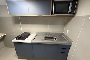 A kitchen with a microwave, stove, and sink.