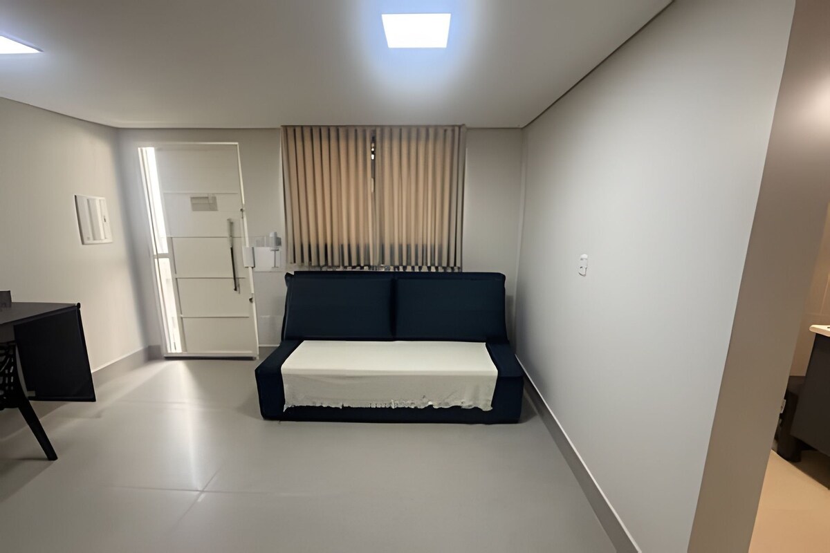 A bedroom with a bed, a desk, and a door.