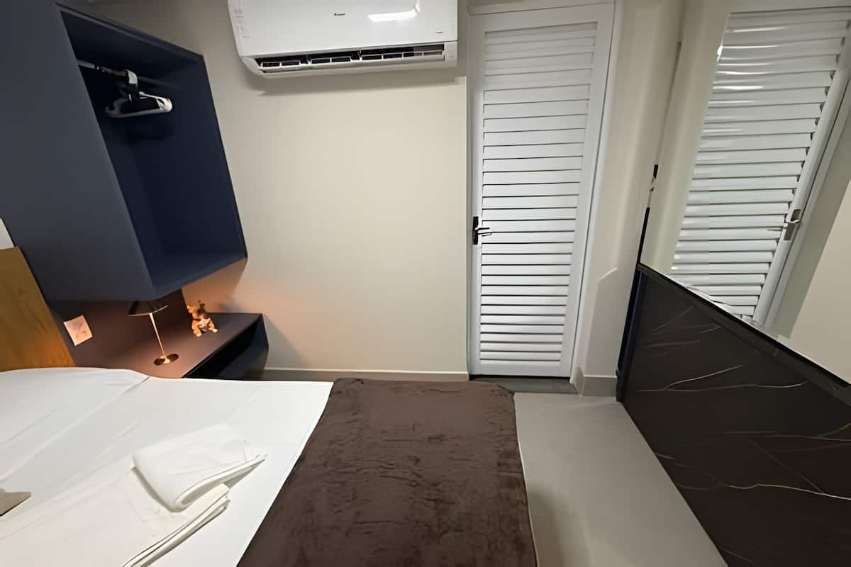 Ett hotellrum med en säng, ett skrivbord, en luftkonditioneringsanläggning och en garderob med skjutdörrar.
