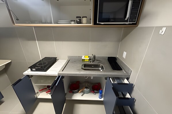 A kitchen with a stove, microwave, sink, and cabinets. - Studios Jocatita (Cuiabá)