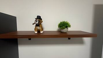 A shelf with a dog figurine and a potted plant.