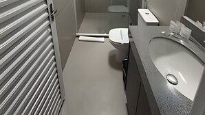 Un baño moderno con inodoro, lavabo y zona de ducha.