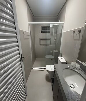 A modern bathroom with a toilet, sink, and shower area. - Studios Jocatita (Cuiabá)