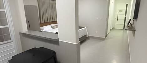 Una habitación moderna y minimalista con una mesa y sillas negras para comer, una pequeña cocina y un televisor montado en la pared.