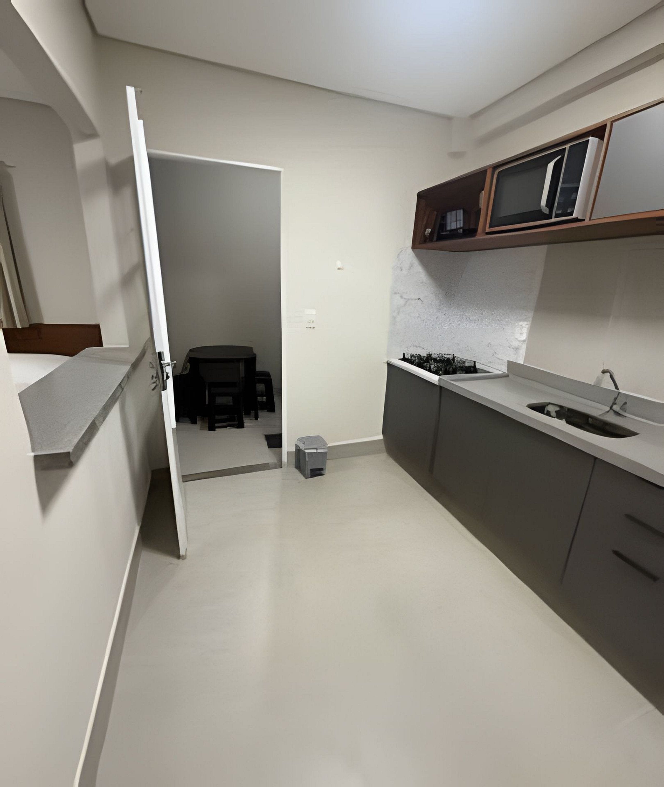 A kitchen with a microwave, cabinets, and a sink. There is a door leading to another room.