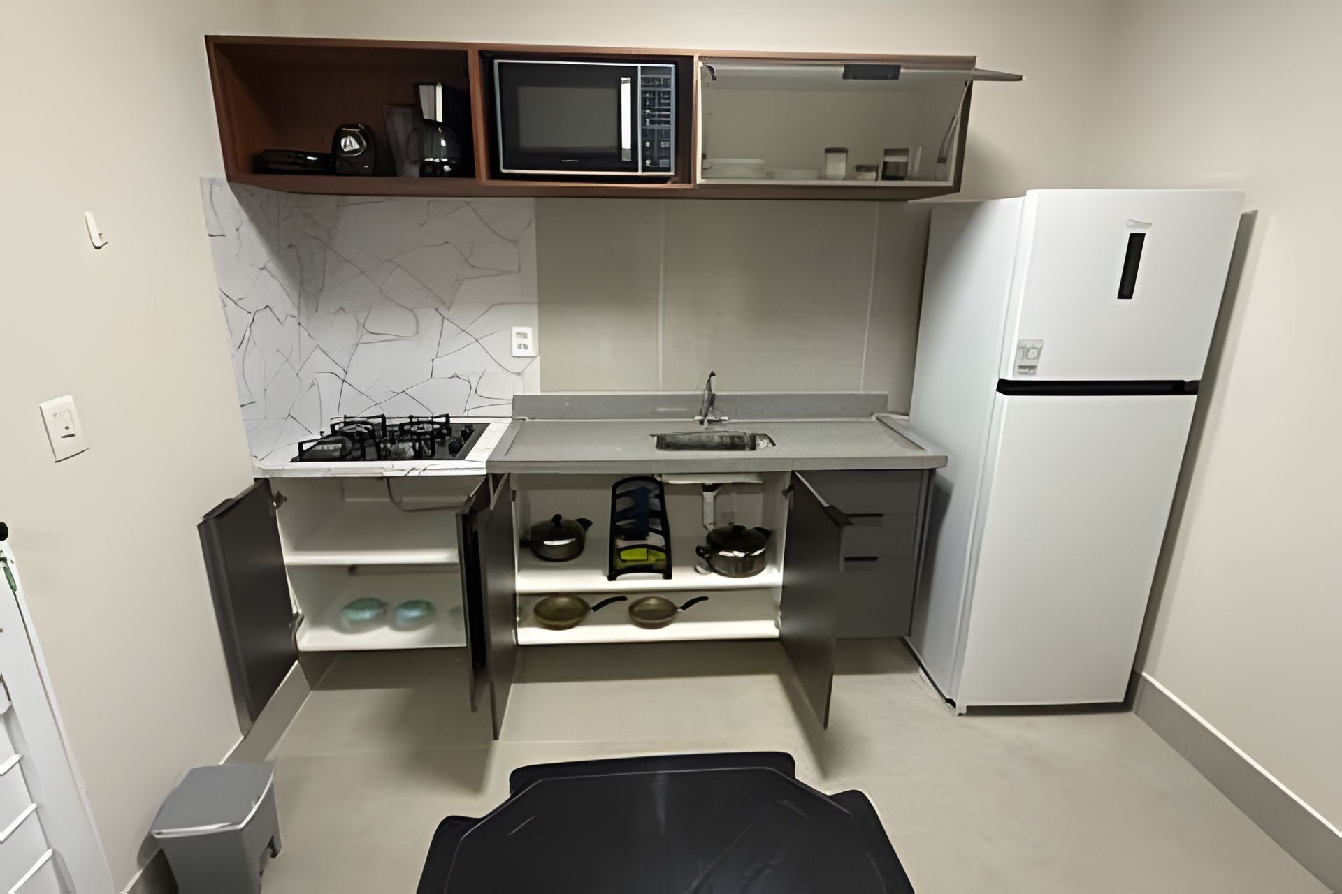 Eine kleine Küche mit Gasherd, Mikrowelle, Spüle und Kühlschrank.