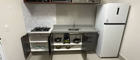 Une cuisine de taille réduite équipée d’une cuisinière à gaz, d’un four à micro-ondes, d’un évier et d’un réfrigérateur.