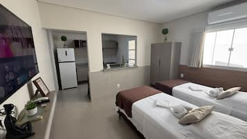 Ett hotellrum med två sängar, en TV, ett litet kök och ett badrum.