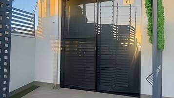 A modern building with a black gate, a small green area, and a wall with a vertical garden.