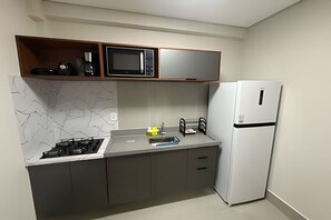 A compact kitchen with a microwave, stove, and refrigerator. - Studios Jocatita (Cuiabá)