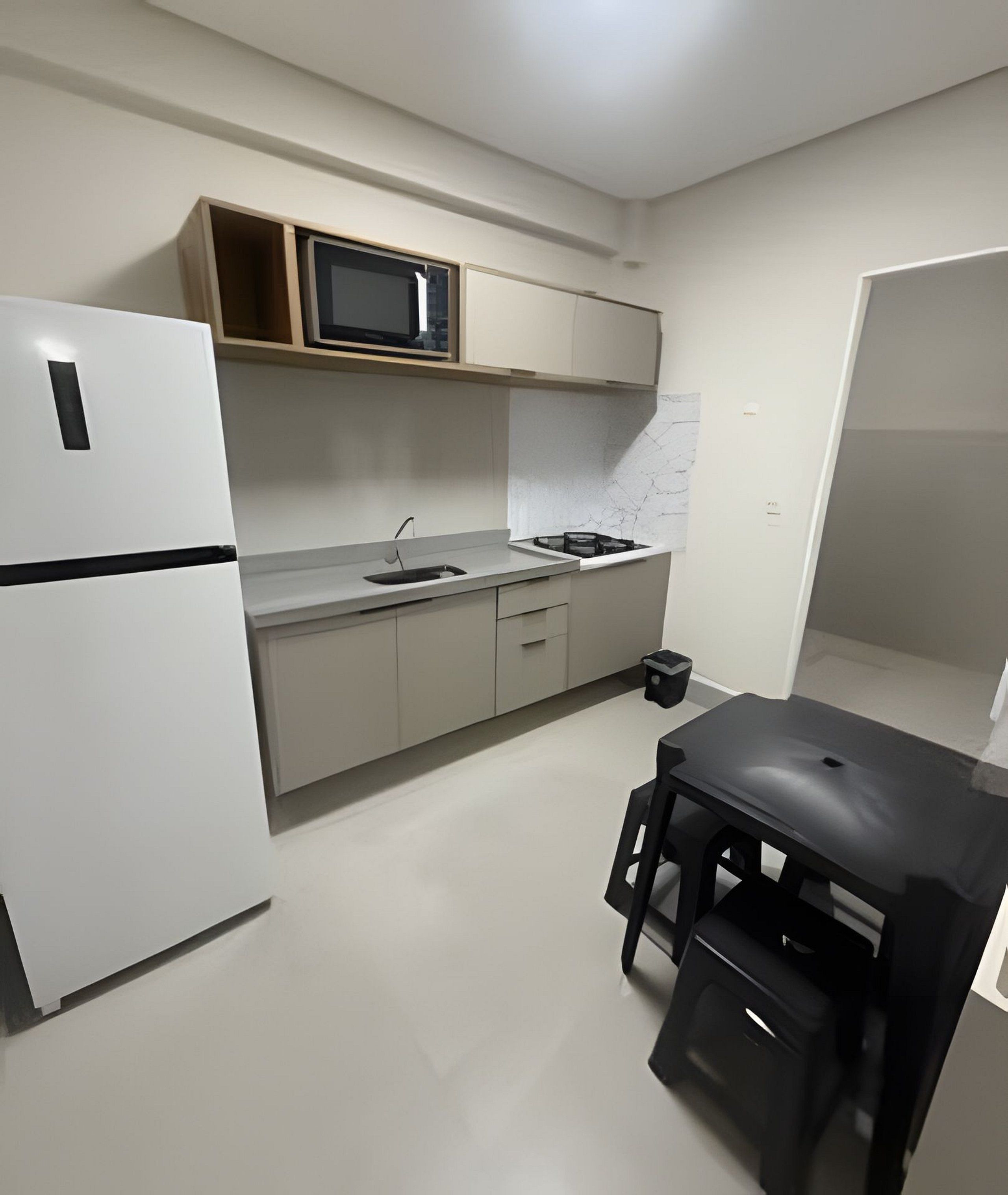 A compact kitchen with a refrigerator, microwave, sink, and a small dining table.