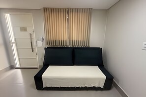 A bedroom with a bed, a door, and a window with curtains. - Studios Jocatita (Cuiabá)