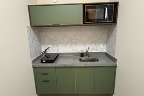 A compact kitchen with a marble backsplash, a sink, and green cabinetry. - Studios Jocatita (Cuiabá)