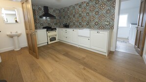 Une cuisine avec des meubles blancs, une cuisinière noire et un dosseret à motifs.