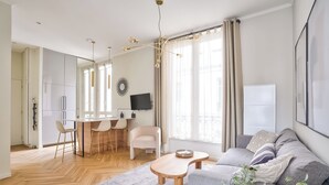 A modern living room with a sofa, a coffee table, and a dining area with chairs and a TV.