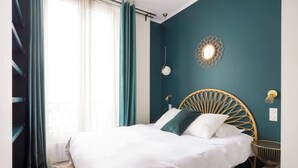 A neatly made bed with white bedding, a round wooden headboard, and a small bedside table with a lamp.