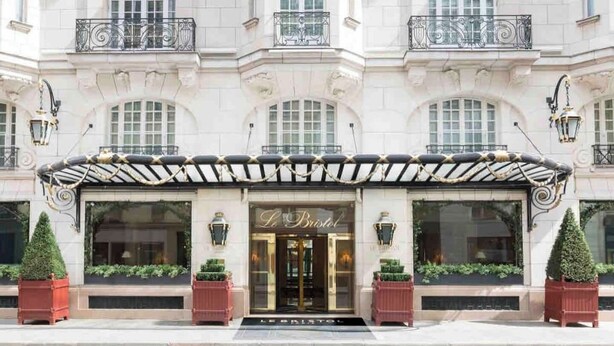 A grand building with a classic facade, large windows, and a prominent entrance with a sign reading "L'Hôtel Bristol".