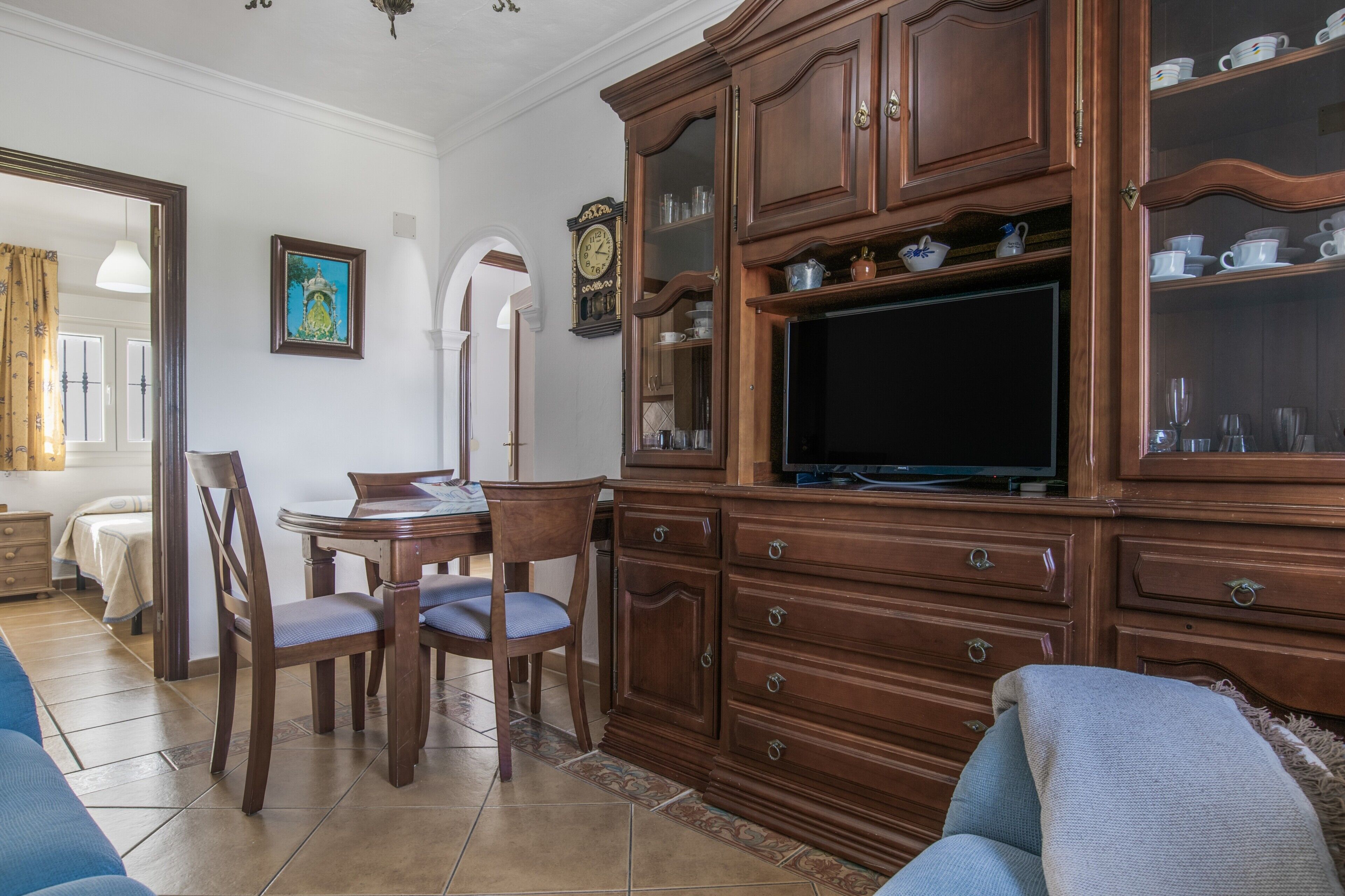 Sala de estar con un mueble de madera, televisión y zona de comedor.