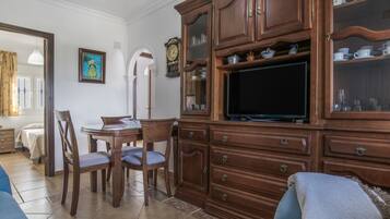 Sala de estar con un mueble de madera, televisión y zona de comedor.