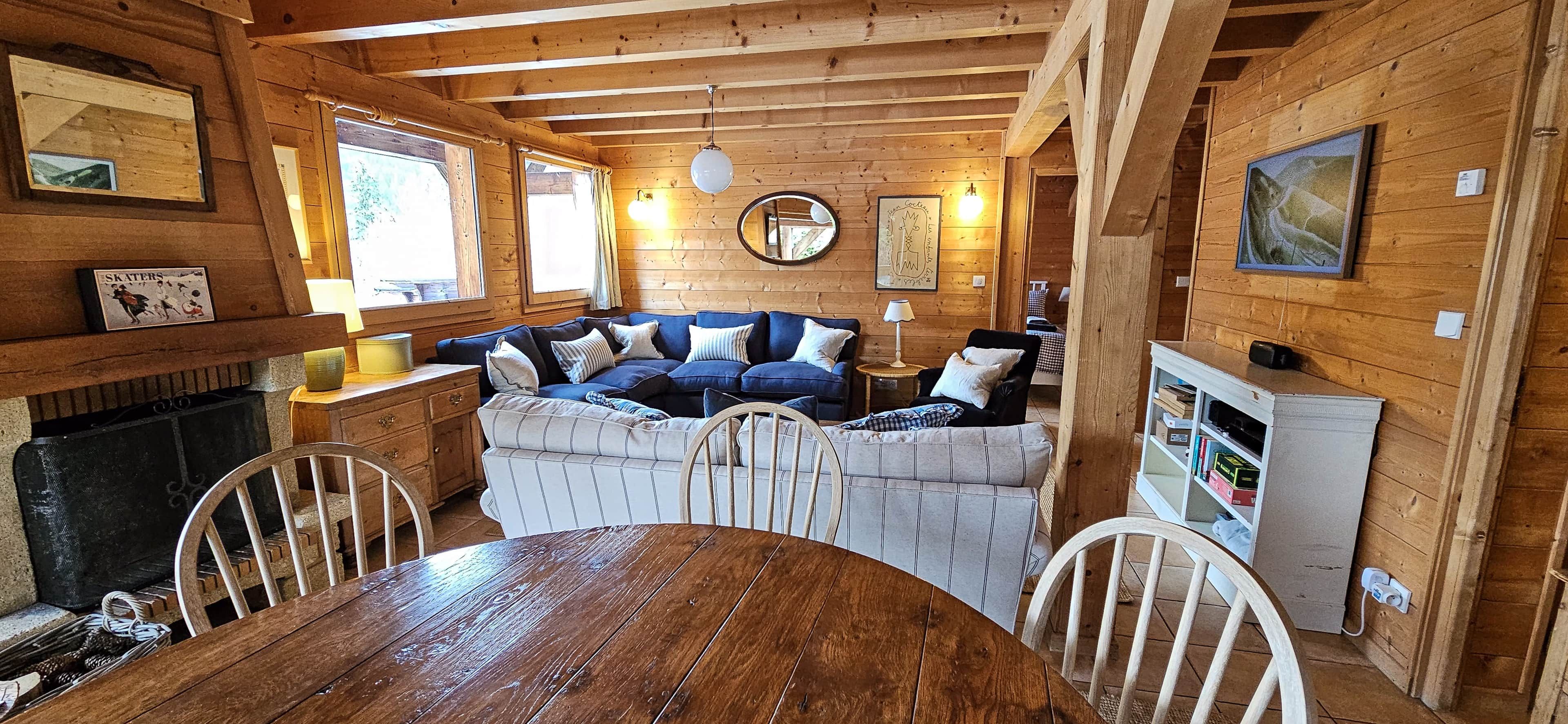 L’intérieur d’un chalet chaleureux, avec une table à manger en bois, un canapé bleu et une cheminée.