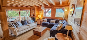 A cozy log cabin interior with a sofa, a dining table, and a fireplace.