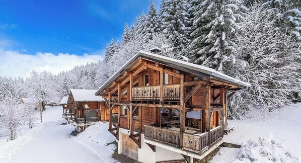 Eine Holzhütte mit Balkon, umgeben von schneebedeckten Bäumen.