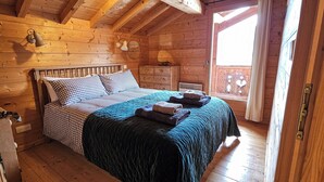 A wooden cabin bedroom with a bed, bedside table, and a window.