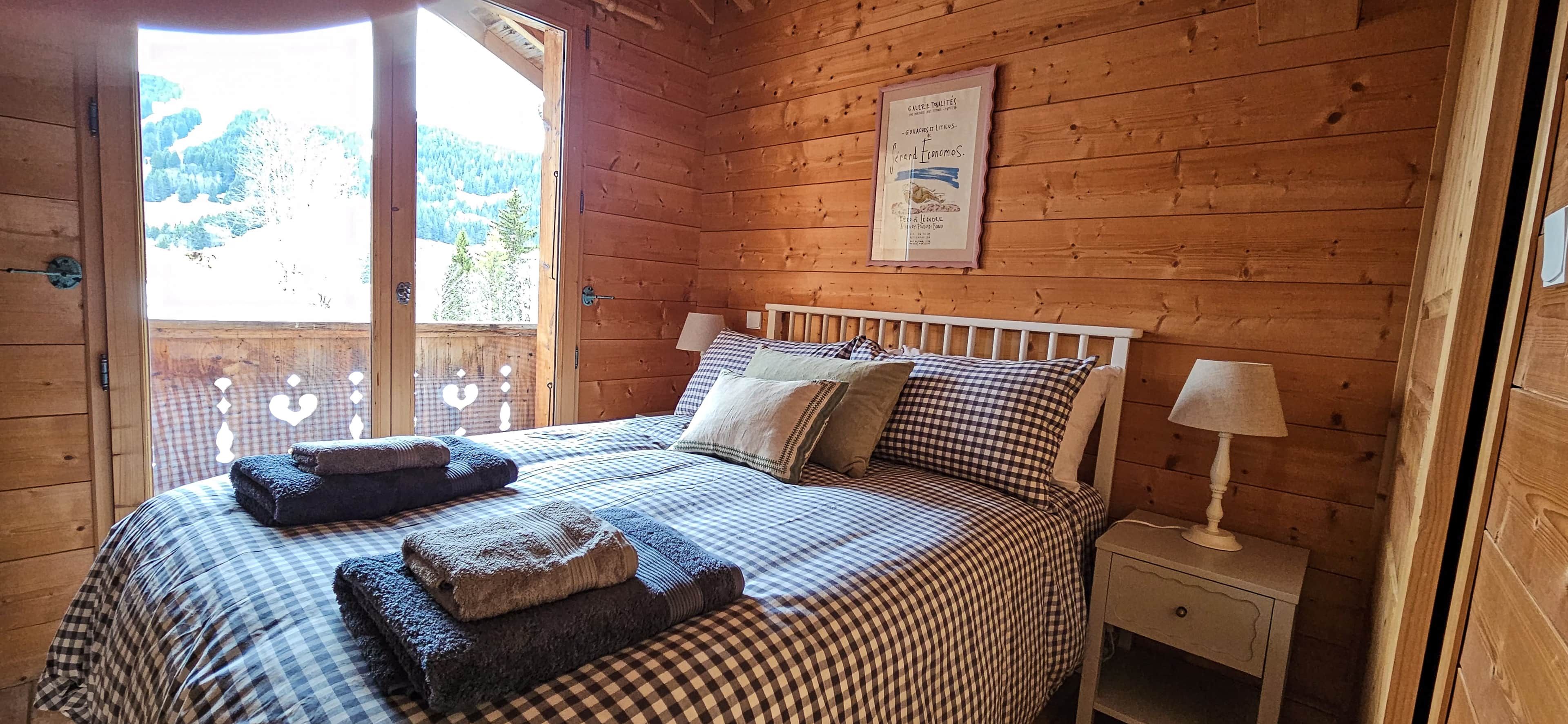 Une pièce en bois avec un lit, des oreillers, une table de chevet et un certificat encadré accroché au mur.