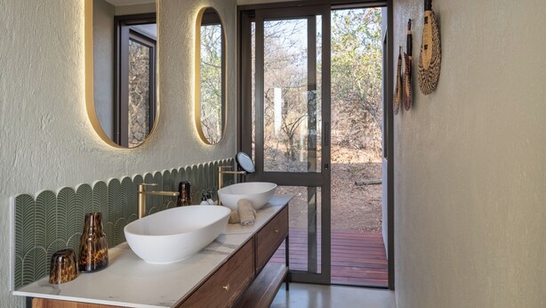 A modern bathroom with two large sinks, a mirror, and a view of the outdoors. - Tintswalo Scops Rest (Hoedspruit)