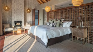 Un dormitorio con una cama grande, una chimenea, un muro tejido y luces colgantes.
