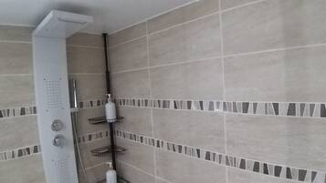 Een douche met een handdouche, een zeepdispenser en een fles shampoo.
