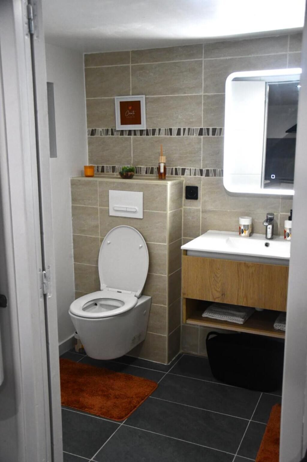 A compact bathroom with a toilet, sink, and mirror.