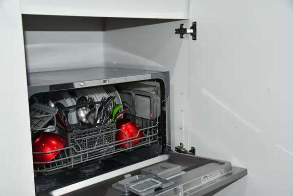 An open dishwasher with various dishes and utensils inside.