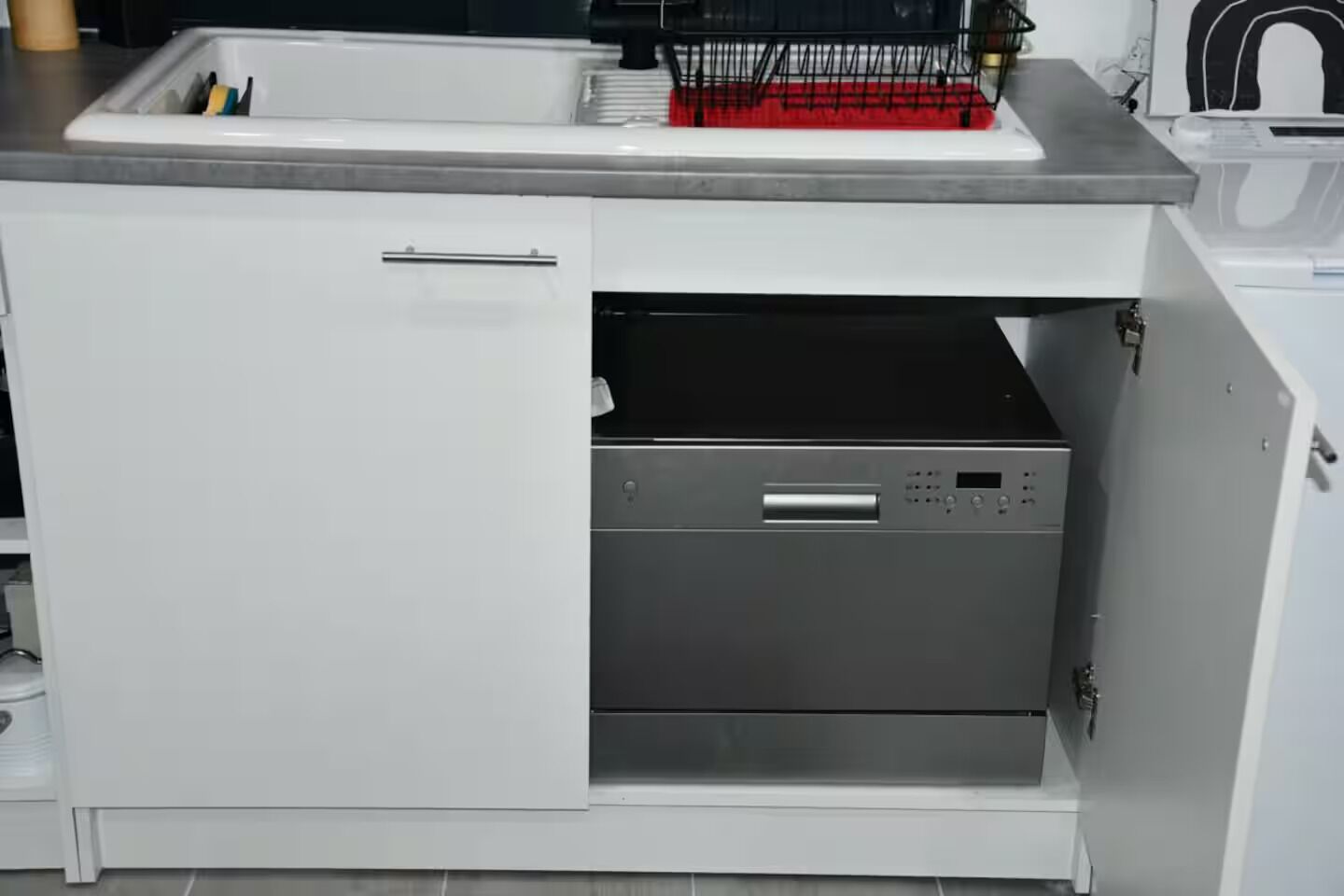 Een keuken met een inbouwvaatwasser, een spoelbak en een kast met een handgreep.