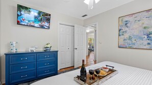 A bedroom with a bed, a dresser, a TV, and a painting. - Bay to Bay Bungalow | Sleeps 6 (Tampa)