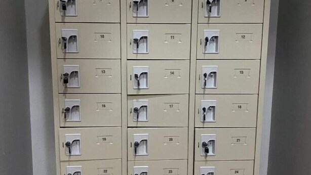 A row of beige lockers with numbered compartments, each with a keyhole. - Hide Hostel (Koh Phangan)